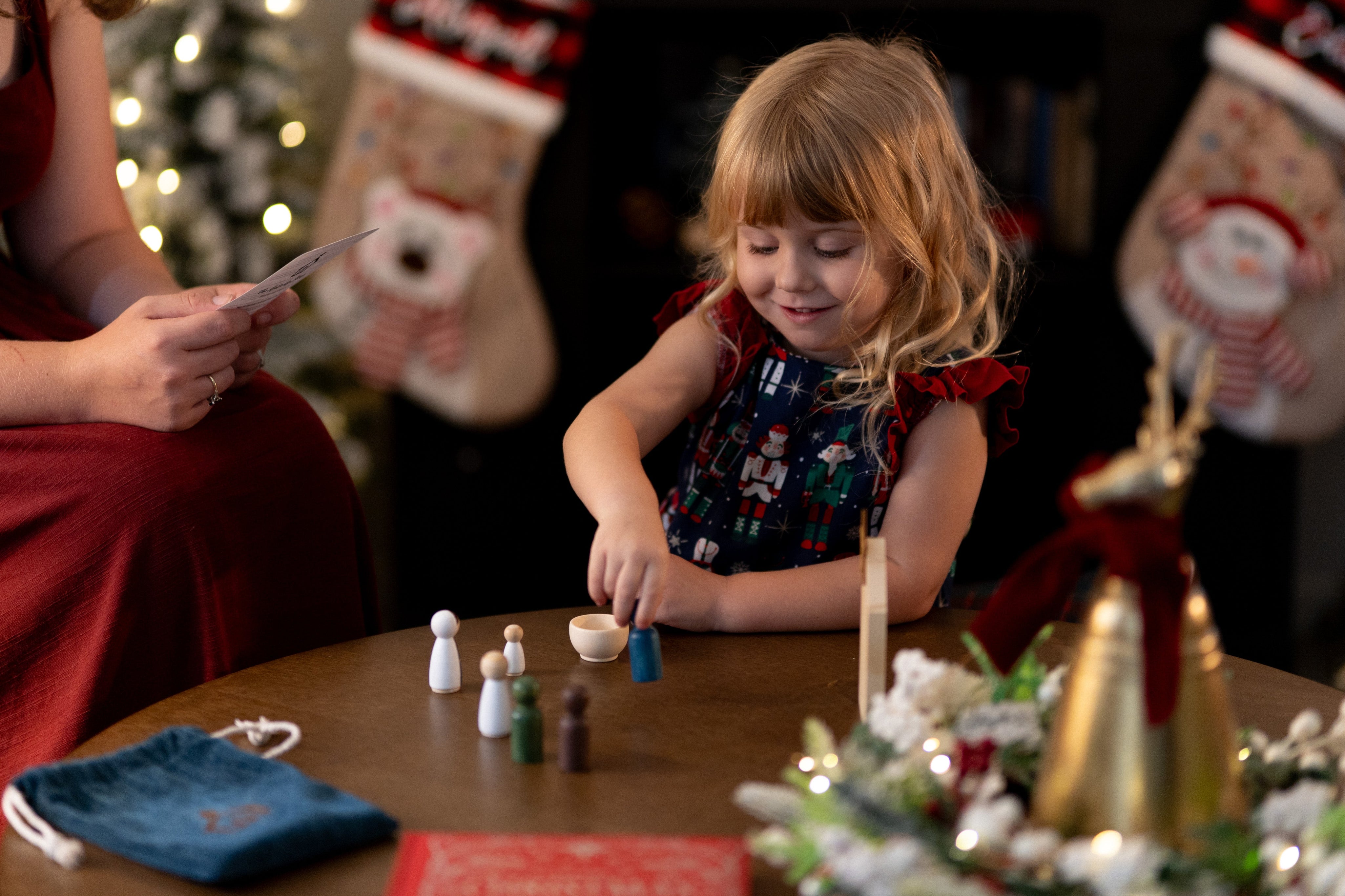 Child playing with Christmas decorations at a table with stockings in the background