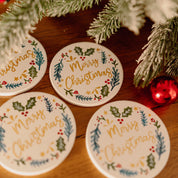Decorative coasters with 'Merry Christmas' text on a wooden surface with festive decorations.