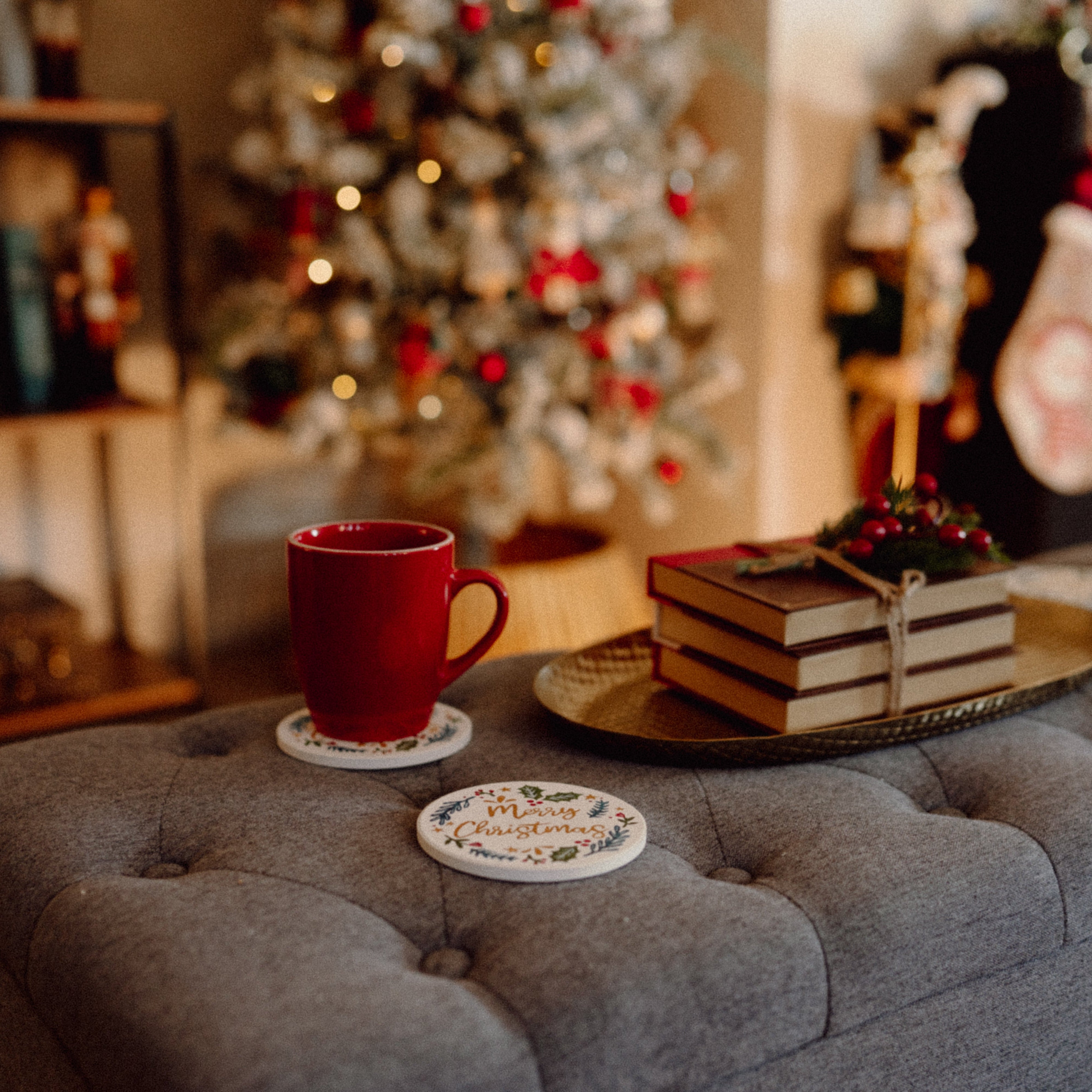 Red mug on a table with a decorated Christmas tree in the background